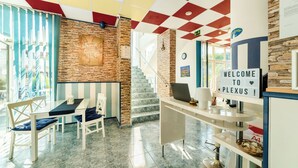 A reception area with a checkered ceiling, a stone wall, a staircase, and a 'Welcome to PLEXUS' sign.
