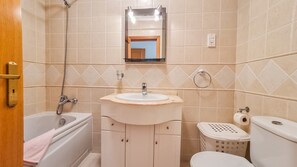 A bathroom with a bathtub, sink, toilet, and a mirror above the sink. - Apartment 'Golfview' with Shared Pool, Wi-Fi and Air Conditioning (Quarteira)