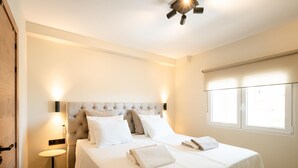 Ein Hotelzimmer mit einem großen Bett, einem Nachttisch, einer Wandleuchte und einem Fenster mit Jalousien.