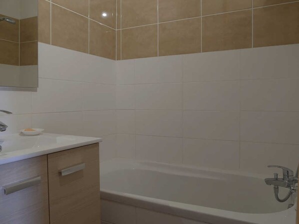 A bathroom with a bathtub, a vanity with a mirror, and a small dish on the counter.