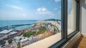 Un paisaje urbano costero con un puente destacado, edificios históricos y una vista a través de una ventana.