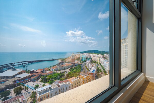 A coastal cityscape with a prominent bridge, historic buildings, and a view through a window. - Mira Home Apartment Hillside Phu Quoc (Phu Quoc)