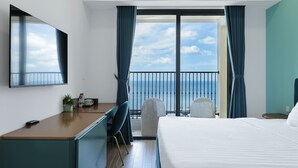 A hotel room with a large bed, a desk, a chair, a TV, and a balcony with a view of the sea. - Mira Home Apartment Hillside Phu Quoc (Phu Quoc)
