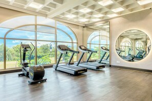 A gym with treadmills, elliptical machines, and a large mirror.