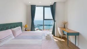 Ein Schlafzimmer mit Bett, Schreibtisch, Stuhl und Meerblick.