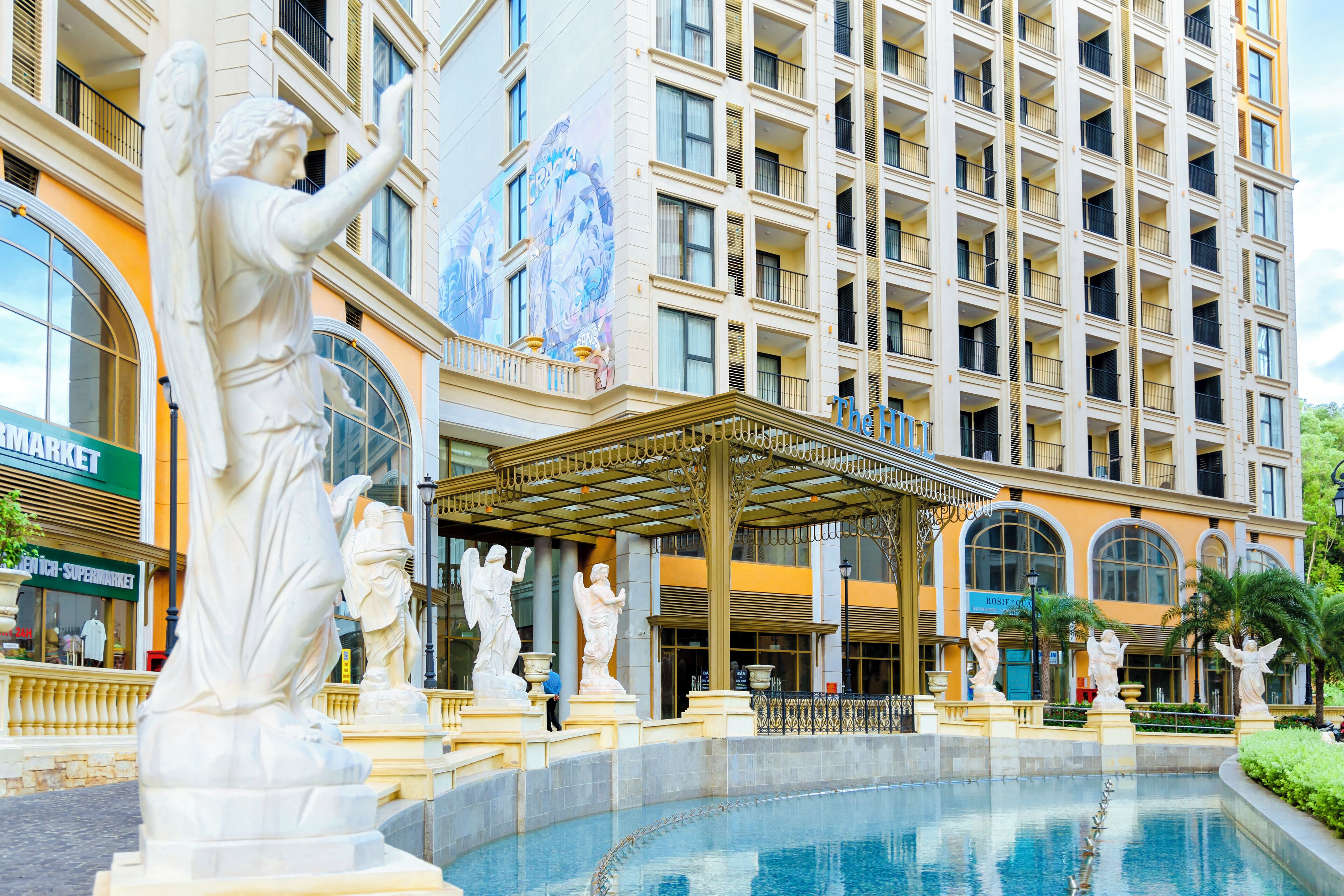 Um hotel com piscina, estátuas e um mural na fachada.