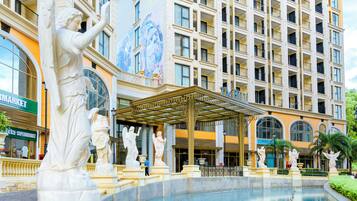 Um hotel com piscina, estátuas e um mural na fachada.