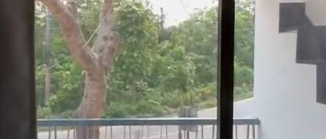 Un balcón con una silla y una mesa, un árbol afuera y una escalera en la pared.