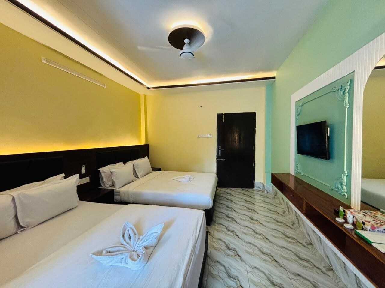 A hotel room with two beds, a marble floor, a TV, and a mirror.