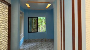 Une pièce avec un mur bleu, une fenêtre donnant sur un paysage verdoyant et un sol à motifs de marbre.
