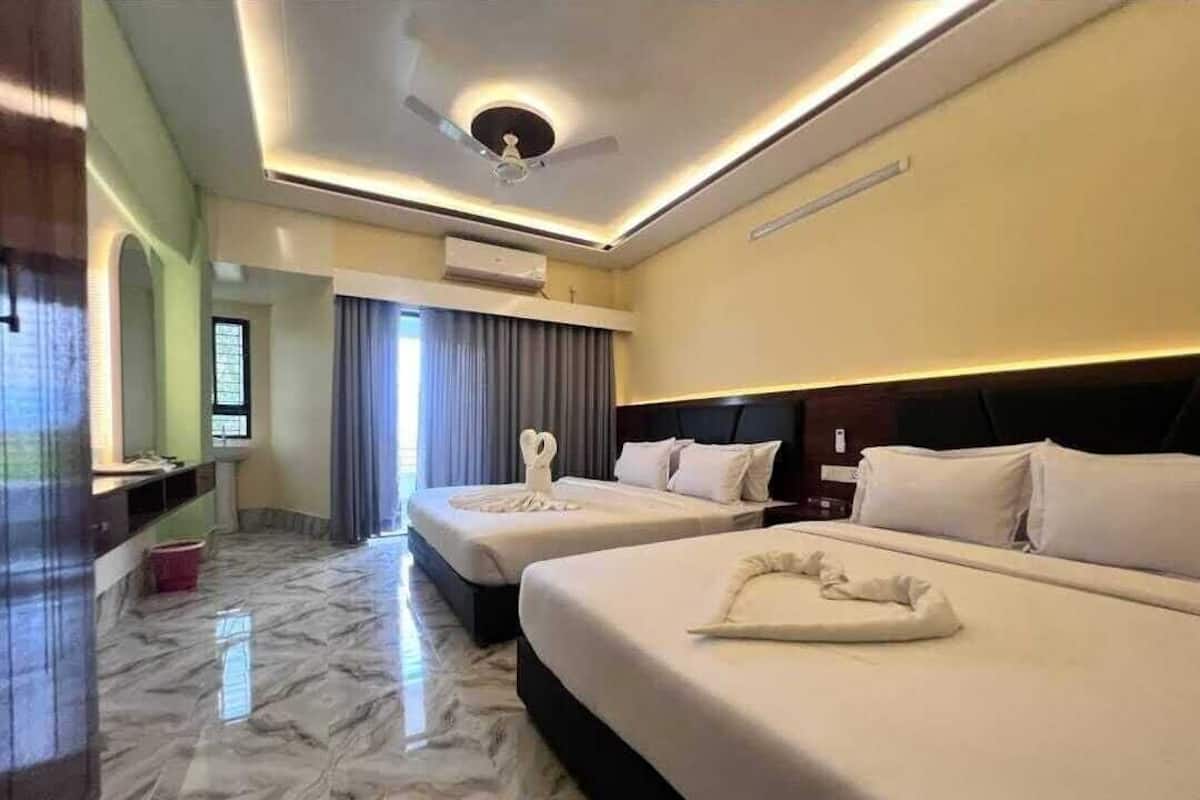 Une chambre d’hôtel avec deux lits, un ventilateur de plafond, un sol en marbre et une grande fenêtre avec des rideaux.