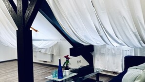 Een moderne loft slaapkamer met een schuine plafond, een glazen salontafel, een bed en een potplant.