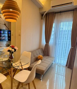 Una sala moderna con un sofá, sillas, una mesa de vidrio y un televisor.