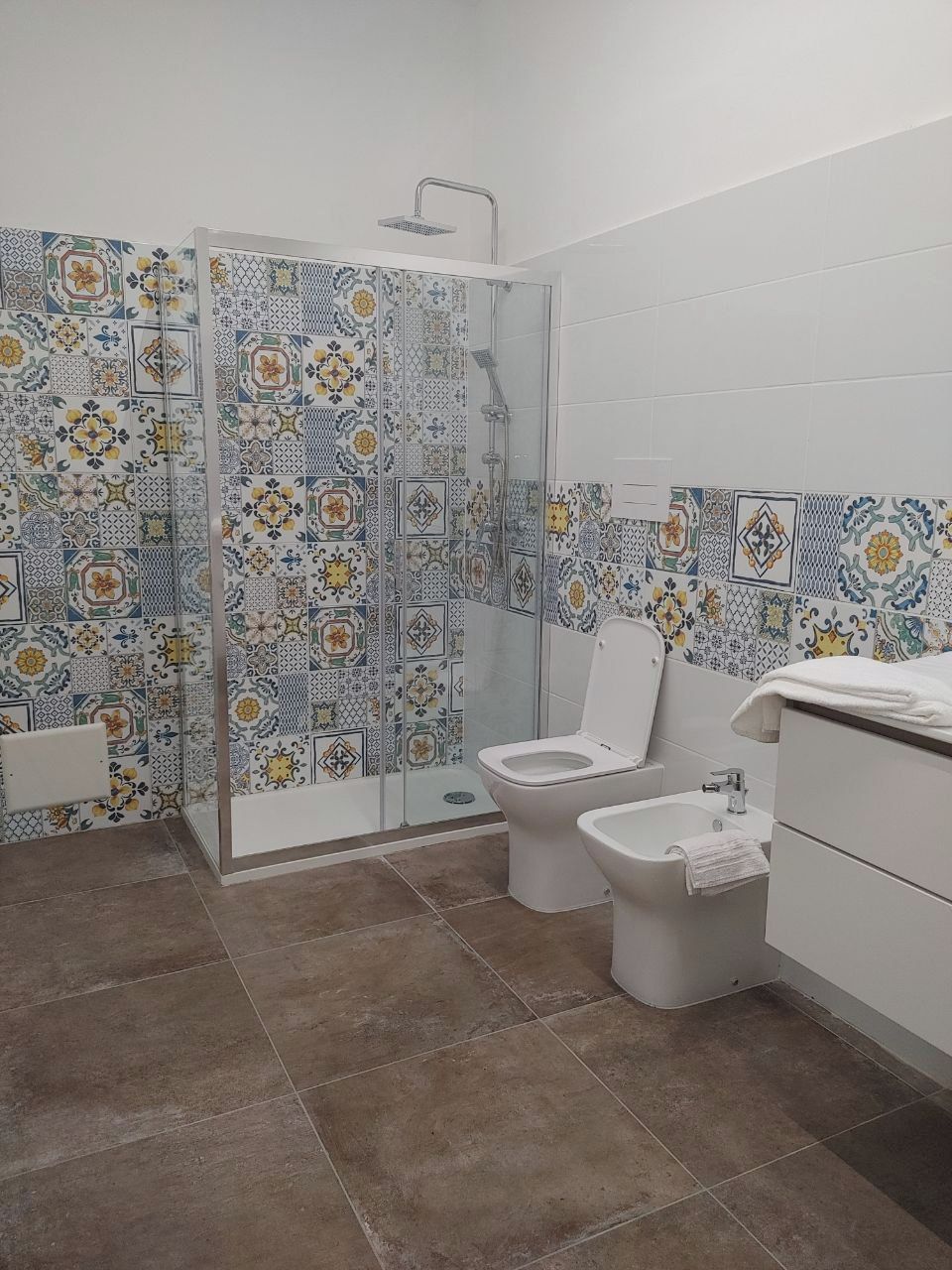A bathroom with a shower, toilet, bidet, and a sink.