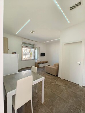 Una cucina moderna con zona pranzo, una TV a parete e una porta che dà su un'altra stanza.