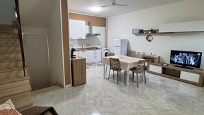 A modern living room with a dining area, a kitchen in the background, and a staircase leading to another level. - Sole d'Otranto, independent apartment in Otranto (punta area) 500m from the sea (Otranto)