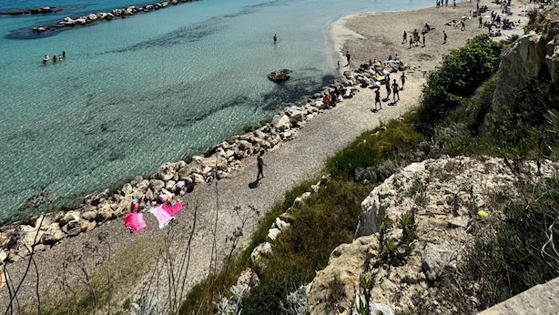 A coastal beach with clear waters, rocky shoreline, and a distant town. - Sole d'Otranto, independent apartment in Otranto (punta area) 500m from the sea (Otranto)
