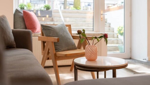 Un salon moderne avec un canapé, un fauteuil, une petite table et un vase rempli de fleurs.