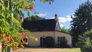 A house with a tiled roof, a front door, and a small garden with flowers and shrubs. - Spacious gîte in idyllic wooded setting by a stream with hammock & barbecue (Cronat)