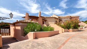 A building with a sloped roof, a chimney, and a paved entrance area with a planter.