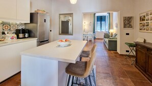 A kitchen with a central island, a refrigerator, and a coffee maker.