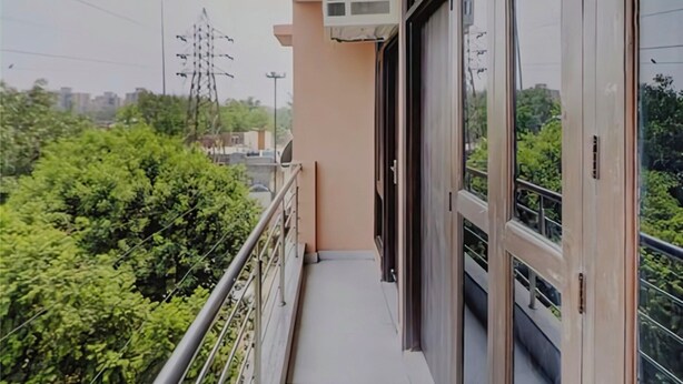 A balcony with a glass door, a window, and an air conditioning unit. - Star Light Inn (New Delhi)