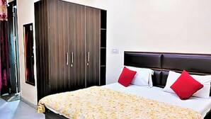 A bedroom with a bed, a wardrobe, and a door. - Star Light Inn (New Delhi)