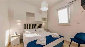 A bedroom with a bed, bedside tables, a chair, and a window.
