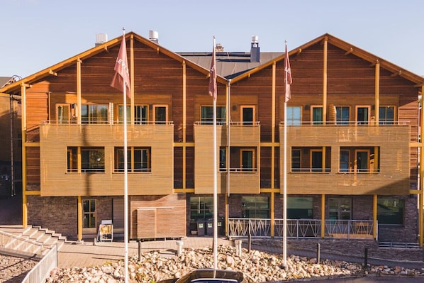 Ein mehrstöckiges Holzgebäude mit Balkonen, großen Fenstern und einem Steinfundament.