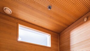 Una sala de sauna con listones de madera en las paredes, una ventana y un banco.