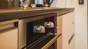 Una cocina moderna con electrodomésticos de acero inoxidable, horno empotrado y un letrero rojo de seguridad contra incendios en la pared.