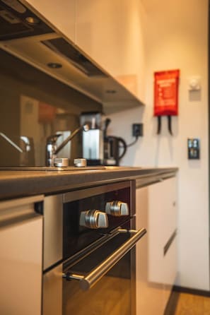 Eine moderne Küche mit Edelstahlgeräten, einem eingebauten Backofen und einem roten Brandschutznachweis an der Wand.