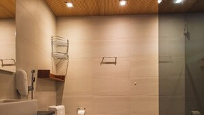 Un baño moderno con techo de madera, inodoro, lavamanos y zona de ducha.