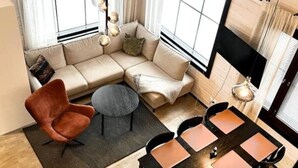 Un espace de vie compact comprenant un canapé, un fauteuil, une table basse ronde et un coin repas avec une table et des chaises.