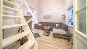 A modern living room with a staircase, a grey sofa, and a coffee table. - Cozy apartment in the center of Levi (Levi)