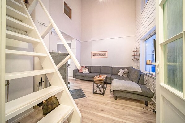 A modern living room with a staircase, a grey sofa, and a coffee table.