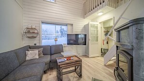 A cozy living room with a grey sofa, a TV, a wooden coffee table, and a fireplace. - Cozy apartment in the center of Levi (Levi)