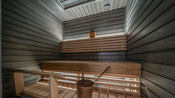 A sauna with wooden benches, a bench with a towel, and a bucket with a ladle. - Cozy apartment in the center of Levi (Levi)