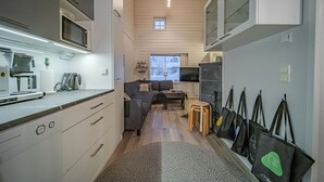 A compact kitchen with modern appliances, a seating area with a sofa and chairs, and a window with a view. - Cozy apartment in the center of Levi (Levi)