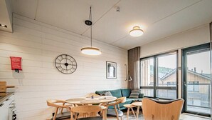 Een moderne woonkamer met een eethoek, grote ramen en uitzicht op gebouwen.