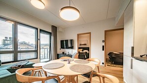 Een moderne eetruimte met een ronde tafel, houten stoelen en een groot raam met uitzicht op gebouwen.