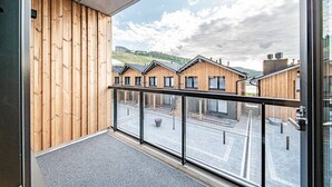 Een balkon met uitzicht op houten gebouwen en een bewolkte lucht.
