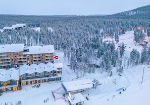 A snow-covered resort with multiple buildings, ski slopes, and a ski lift.