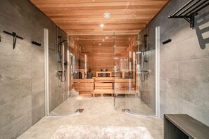 A modern bathroom with a wooden ceiling, glass shower enclosure, and a vanity with a sink and mirror.