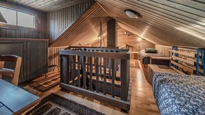A cozy attic bedroom with a sloped ceiling, a wooden crib, a bed, and a desk area.