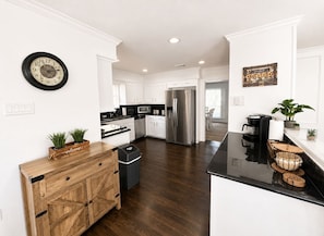 A modern kitchen with white cabinetry, a stainless steel refrigerator, and a black countertop.