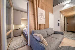 A modern bedroom with a bed, bedside table, and a grey sofa.