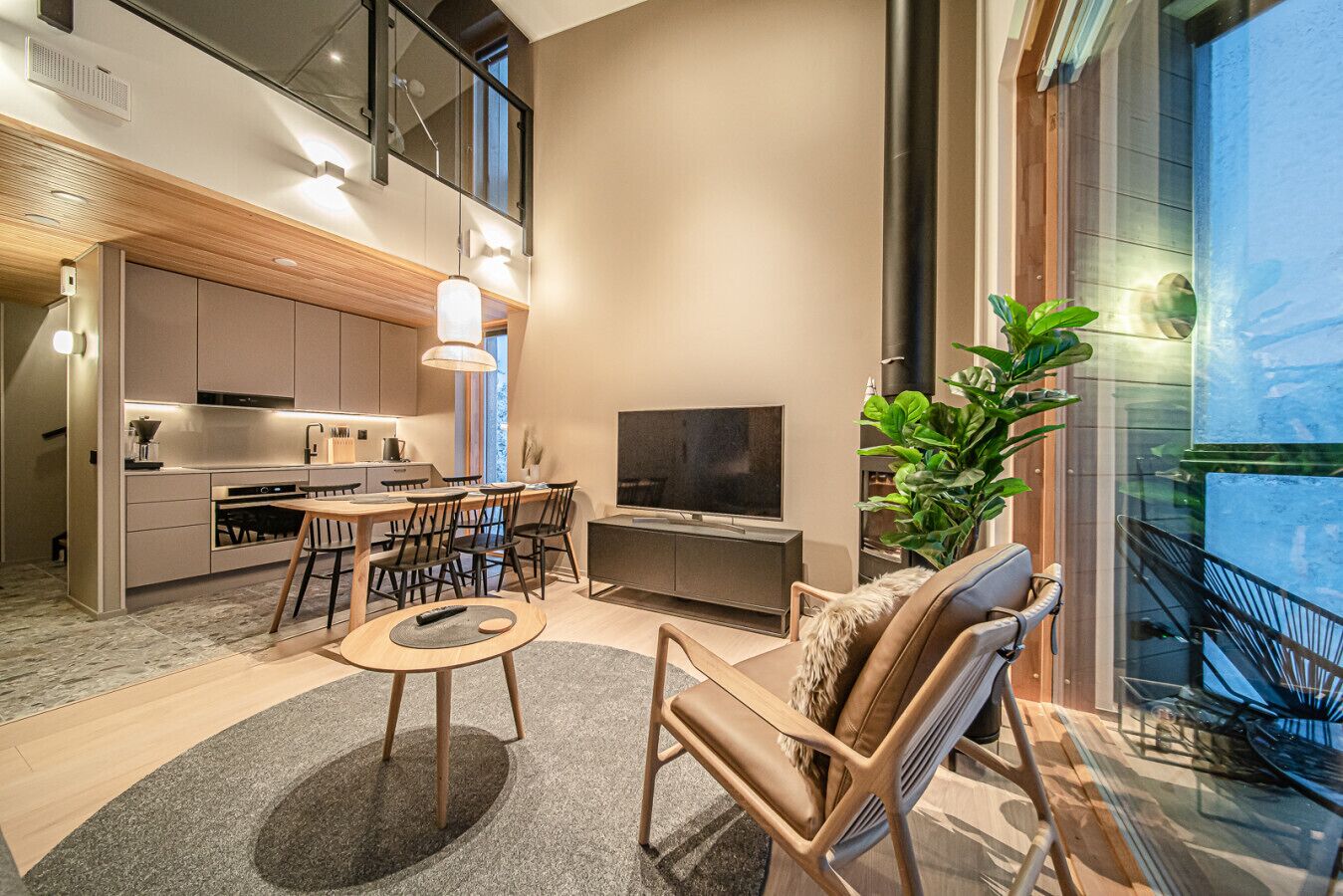 Un espacio habitable moderno con cocina, comedor y zona de estar junto a un ventanal amplio.