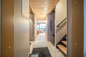Un pasillo moderno con techo de madera, una escalera y vistas a una sala de estar con chimenea.