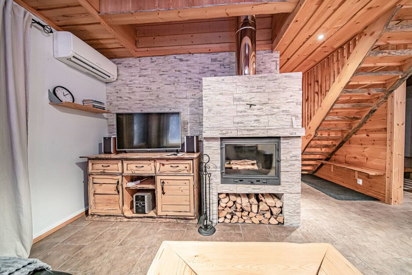 Ein gemütliches Zimmer mit Kamin aus Stein, einem Fernseher und einem Holzschrank.